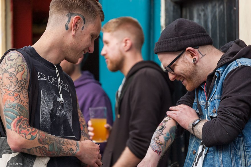 Two tattooed young men outside the Mash Tun pub in Brighton one is showing off his new tattoo 2014 eyeteeth.net