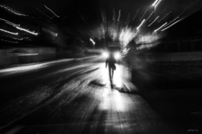 Man on street corner in rain at night with head lights behind him, zoom effect camera shake. Chatham Place Brighton UK. Monochrome Landscape. © P. Maton 2015 eyeteeth.net