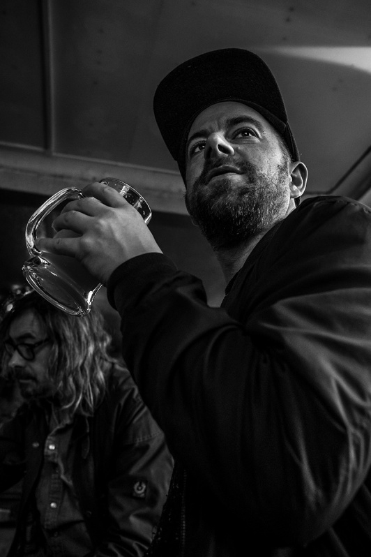 man in baseball cap holding pint tankard of beer at Shakespeare's Head pub Brighton uk. Black and white social documentary portrait. Urban nightlife photography @P. Maton 2017 eyeteeth.net